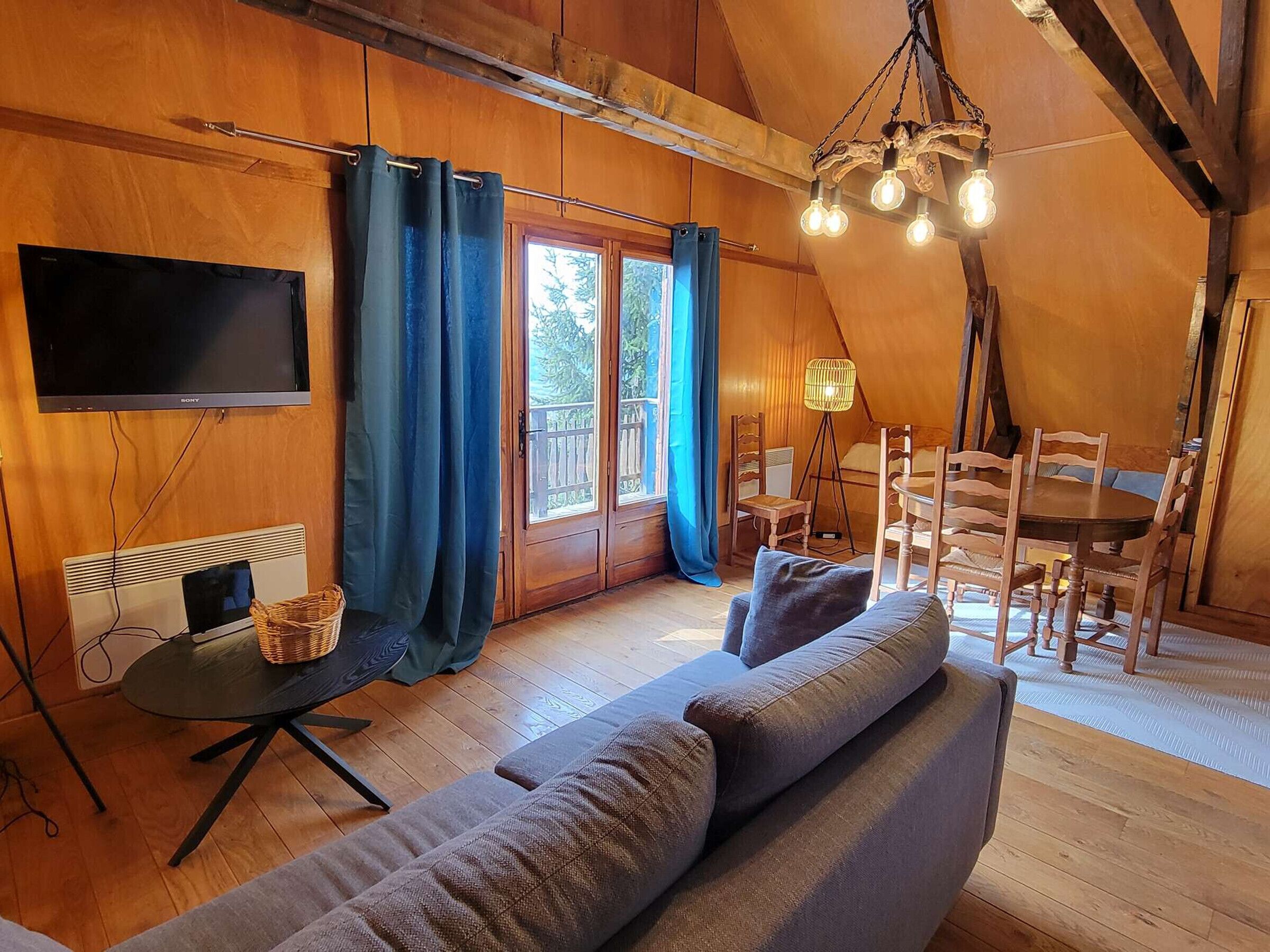 Un intérieur chaleureux, avec des éléments en bois, comprenant un canapé, un téléviseur et un coin repas.