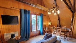 Ein gemütlicher, hölzerner Innenraum mit Sofa, Fernseher und Essbereich.