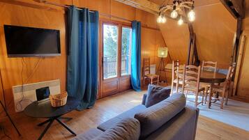 Un intérieur chaleureux, avec des éléments en bois, comprenant un canapé, un téléviseur et un coin repas.