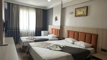 Habitación de hotel con dos camas, un escritorio, una silla, una mesita de noche, una lámpara y un cuadro en la pared.
