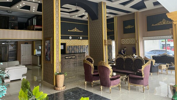 A hotel lobby with a reception desk, seating area, and a view of the street. - Metros Hotel (Mersin)