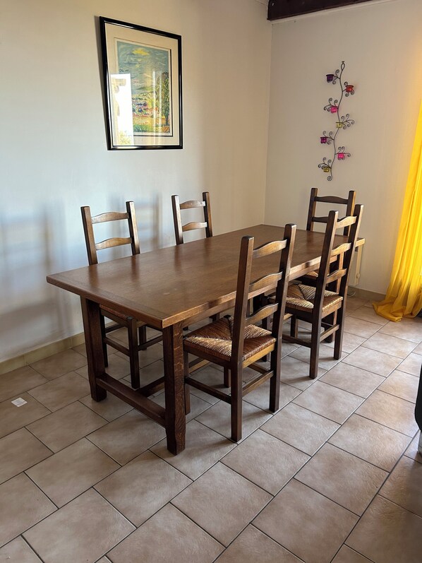 A dining area with a wooden table and chairs, a framed picture on the wall, and a decorative wall piece. - High-quality gîte with breathtaking views (LAMA)