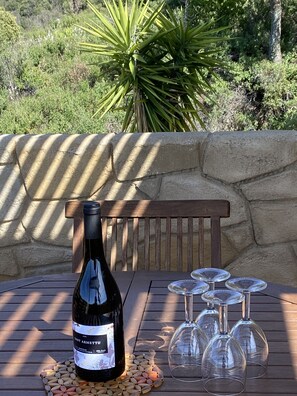 A bottle of wine on a wooden table with empty wine glasses and a decorative coaster. - QUALITY GÎTE WITH BREATHTAKING VIEWS (LAMA)