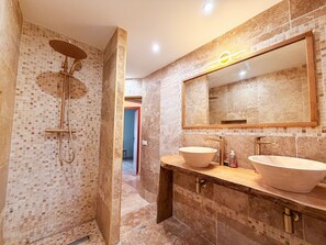 Een badkamer met een inloopdouche, twee wastafels en een grote spiegel.