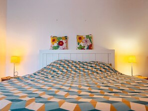A hotel room with a patterned bedspread, two wall-mounted paintings, and two bedside lamps. - Charming Cottage in Heart of La Brenne - 3BR, Fishing Pond, Wi-Fi, Pet-Friendly, All-Inclusive Rates (Communauté de communes Brenne - Val de Creuse-Rosnay)