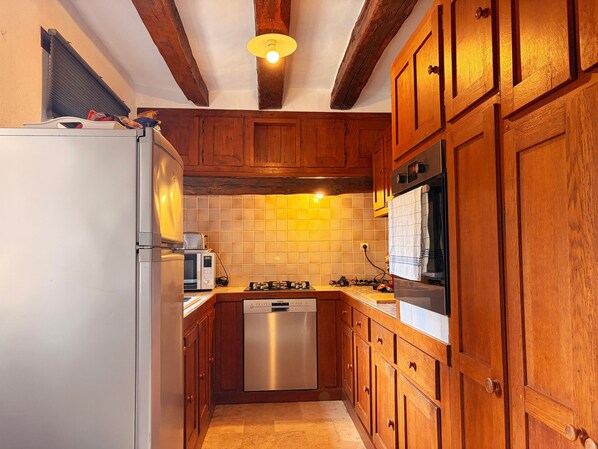 A kitchen with wooden cabinets, a stainless steel refrigerator, a microwave, a dishwasher, and a gas stove. - Charming Cottage in Heart of La Brenne - 3BR, Fishing Pond, Wi-Fi, Pet-Friendly, All-Inclusive Rates (Communauté de communes Brenne - Val de Creuse-Rosnay)