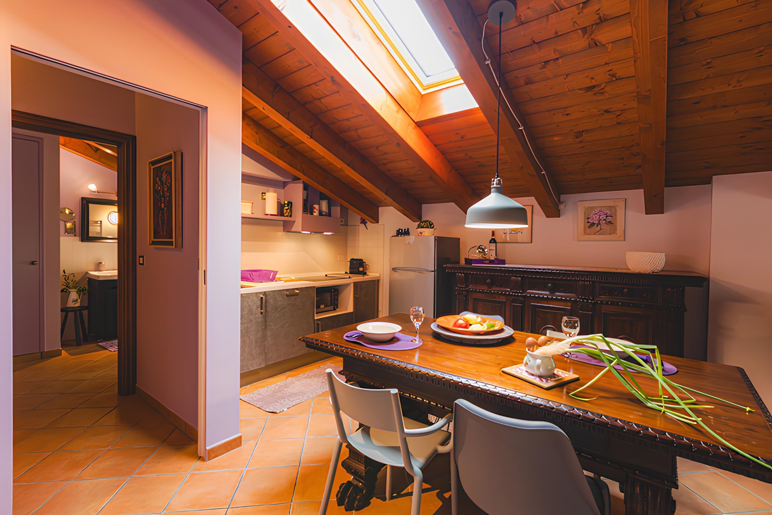 Un espace repas comprenant une table en bois, des chaises et un luminaire suspendu.