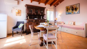 Una sala de estar acogedora con techo de madera, una mesa de comedor con sillas, un sofá y un cuadro en la pared.