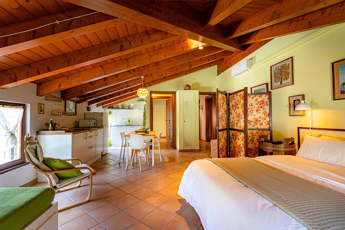A spacious room with a high ceiling, a bed, a dining area, and a kitchen.