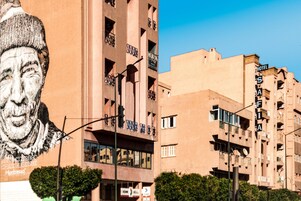 A building with a large mural, balconies, and signage indicating a hotel.