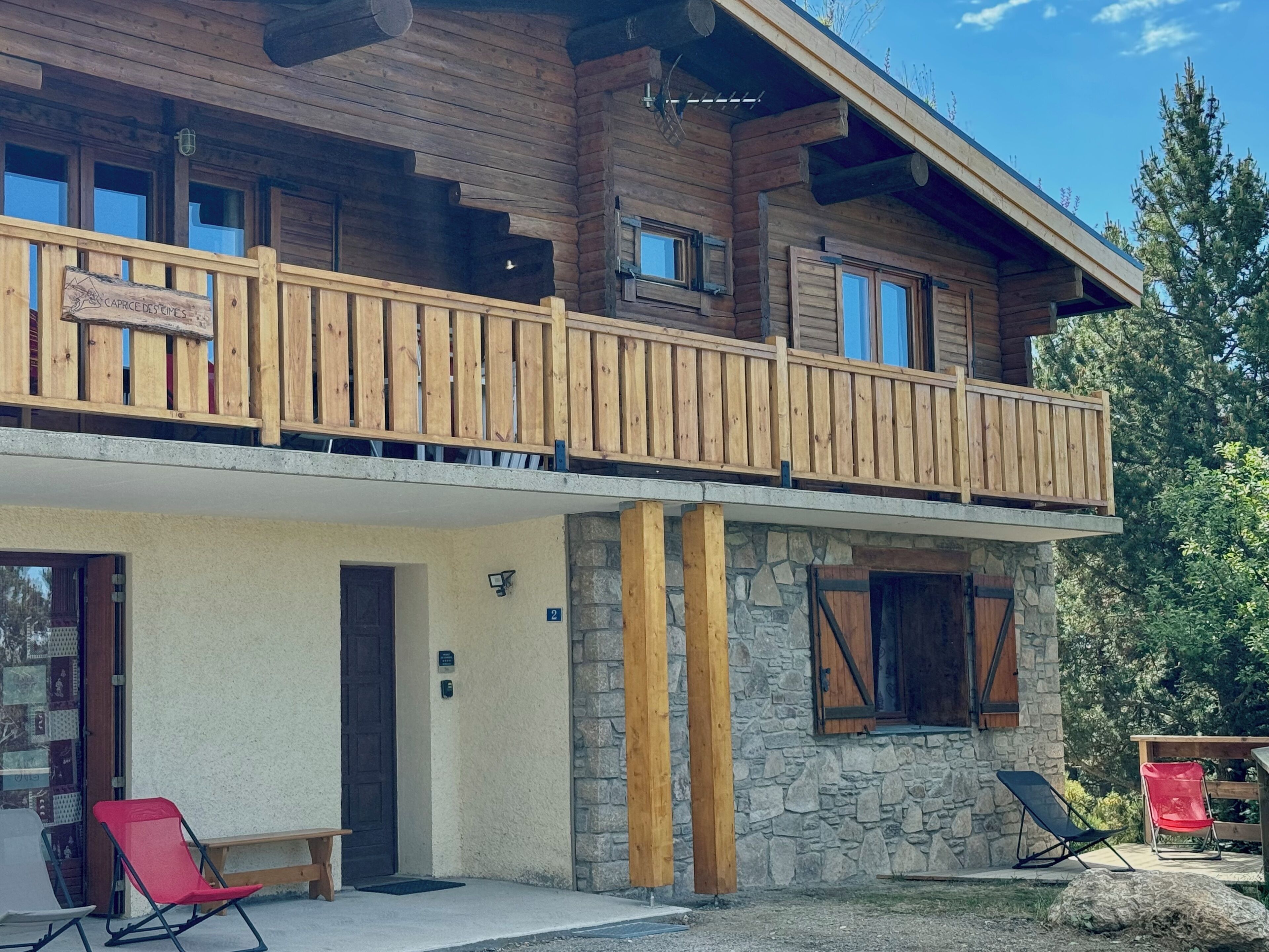 Une cabane en bois dotée d’un balcon, de murs en pierre et d’une enseigne indiquant « Caprice Destines ».