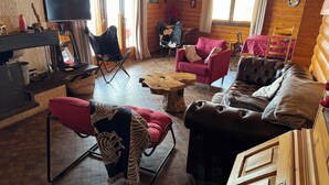 Una habitación acogedora de estilo cabaña con interior de madera, televisión, sofá rojo, sofá de cuero y una mesa de comedor.