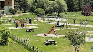 Un parque con juegos infantiles, mesas de picnic y una zona vallada.