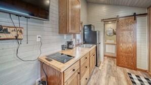 Una cocina con armarios de madera, un microondas, un lavamanos y una estufa.