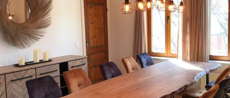 Un espace repas comprenant une table en bois, des chaises et des luminaires suspendus.