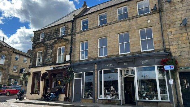 A historic building with multiple shops on the ground floor, including a chocolate shop and a fragrance house. - Angel Lane Apartment. Alnwick Town Centre (Alnwick)