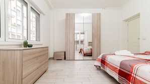 Quarto com cama, cómoda, espelho e janela.