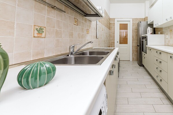 A kitchen with a double sink, stainless steel appliances, and a tiled backsplash.