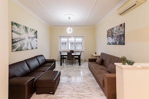 A living room with two brown sofas, a dining table, and a ceiling light.
