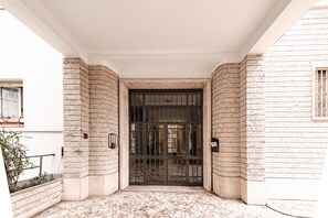 A building entrance with a tiled floor and a large metal gate.