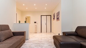 Uma sala de estar moderna com dois sofás, piso de mármore e uma porta que dá para outro cômodo.