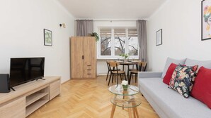 Een moderne woonkamer met een televisie, bank en eethoek.