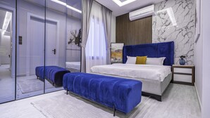 A modern bedroom with a large bed, a bench, a bedside table, and a mirror. - Mabaat - Al Aqiq - 504 (Riyadh)