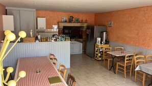 Une cuisine compacte dotée d’un îlot central, un coin repas avec une nappe à carreaux et un espace salon confortable.