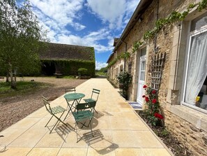 A courtyard with a table and chairs, a stone building with windows, and a tree. - PRESBYTERY: SPIRITUAL-REPOSANT:Property in the countryside, close to footpaths (Rouperroux-le-Coquet)