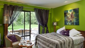 A hotel room with a bed, a chair, a table with tea set, and a view of the outdoors. - Hôtel la Source Bleue (Gudmont)