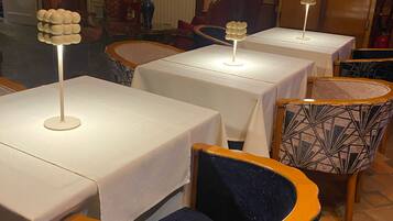 Un comedor con mesas y sillas, un radiador y un cuadro en la pared.
