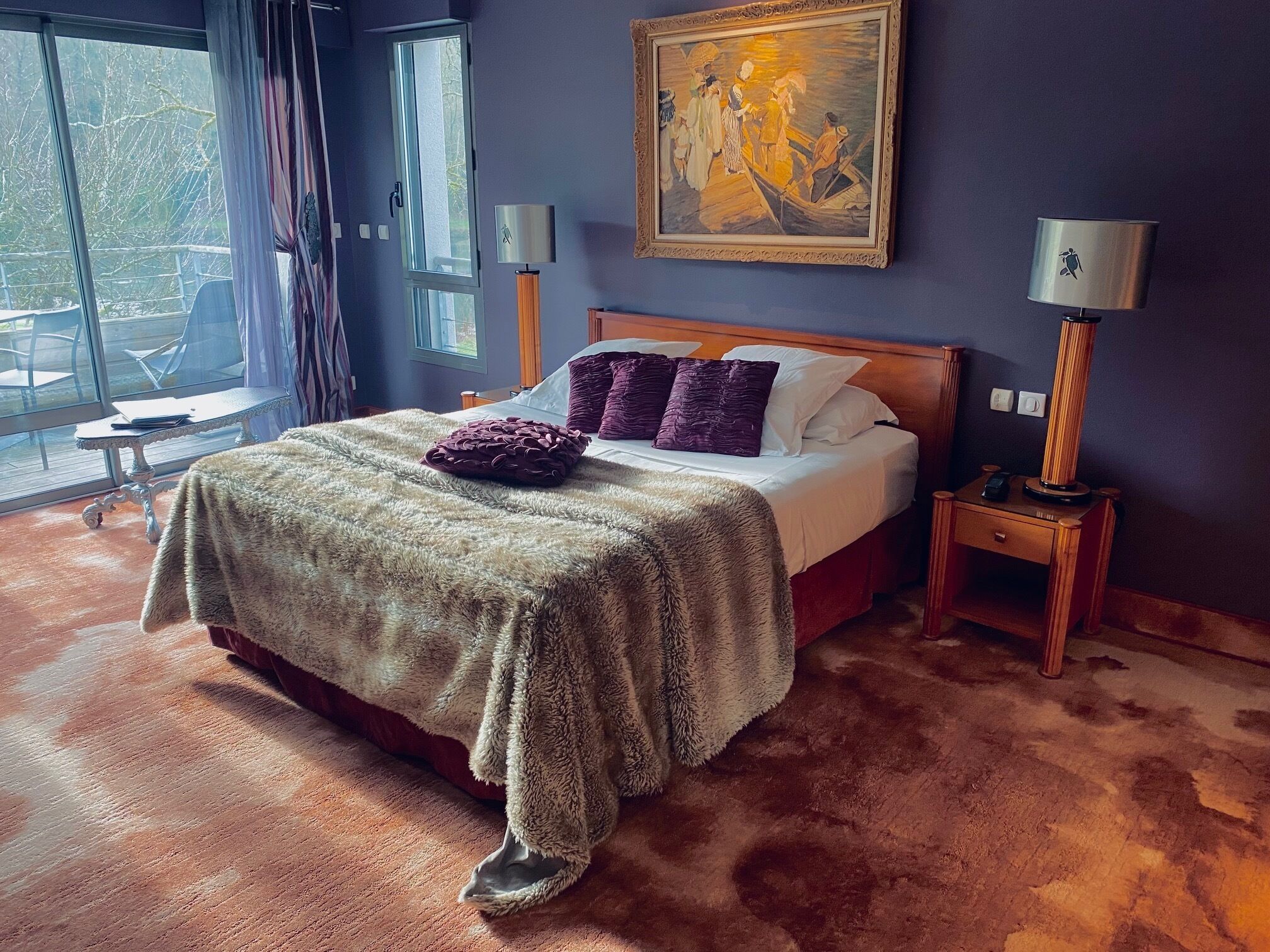 Ein Schlafzimmer mit einem großen Bett, einem Bild an der Wand und Blick ins Freie durch das Fenster.
