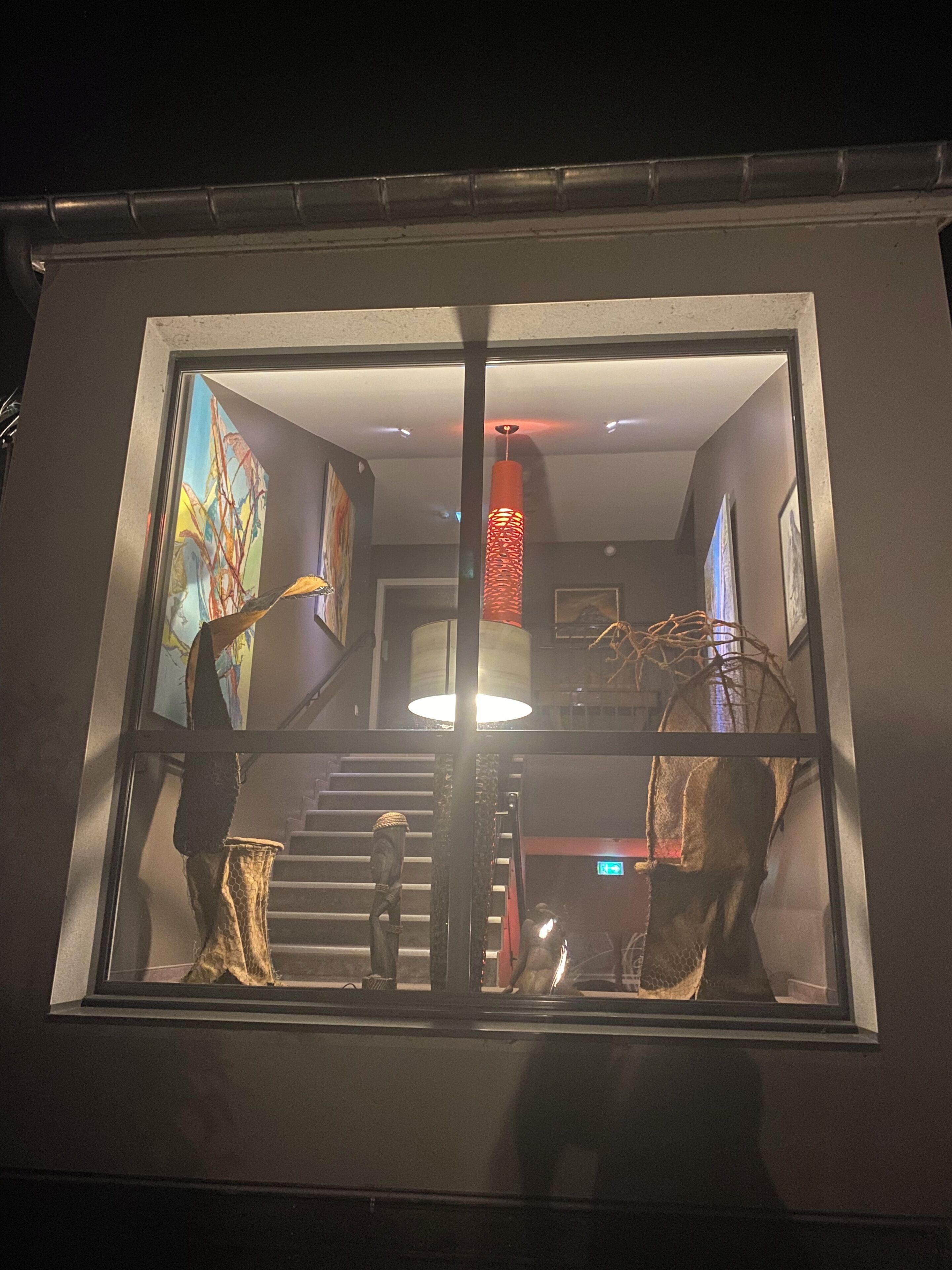 Een modern interieur met een trap, een groot raam en abstracte kunst.