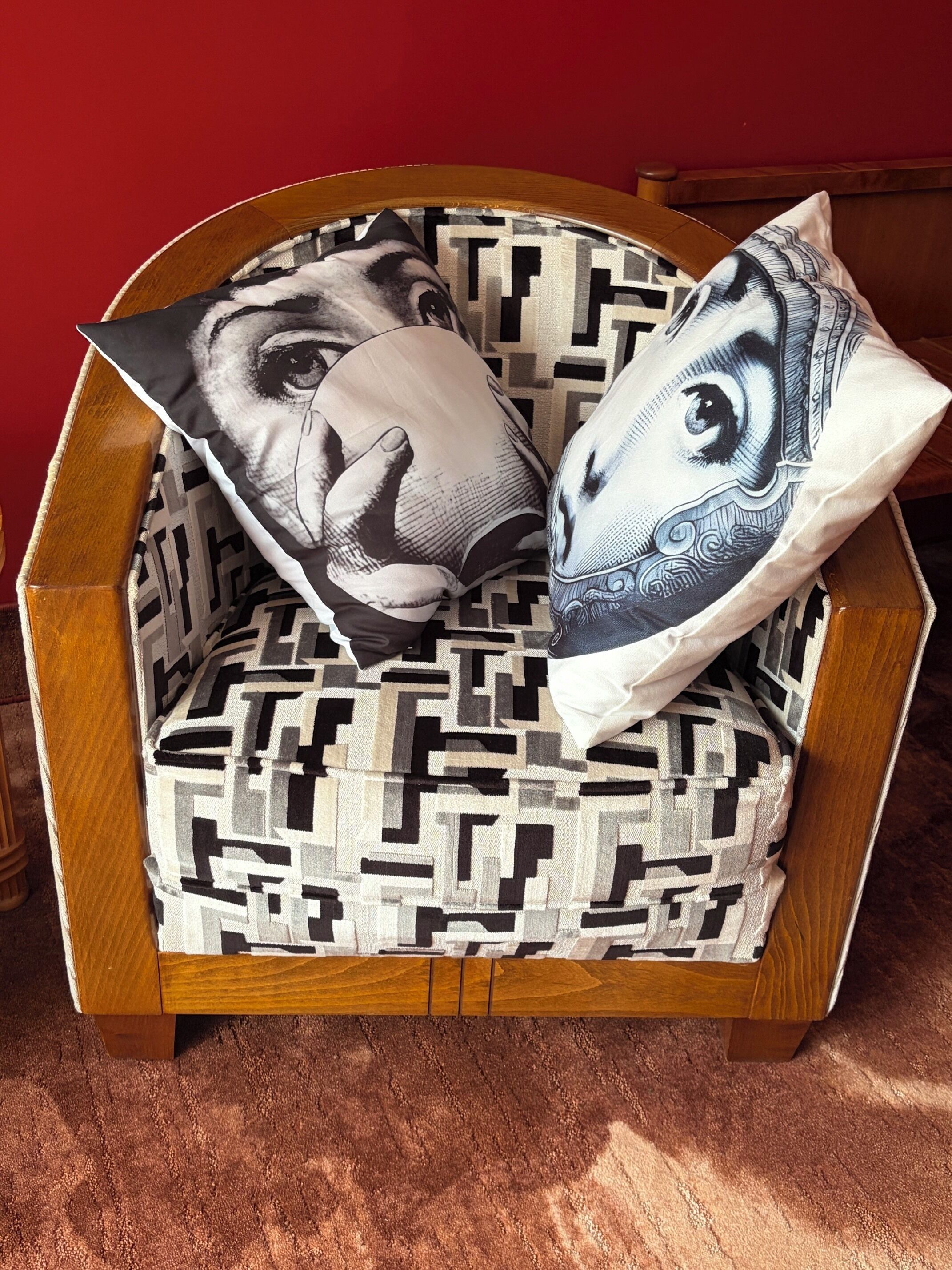 Una sedia con un cuscino a motivi geometrici e due cuscini decorati con disegni artistici.