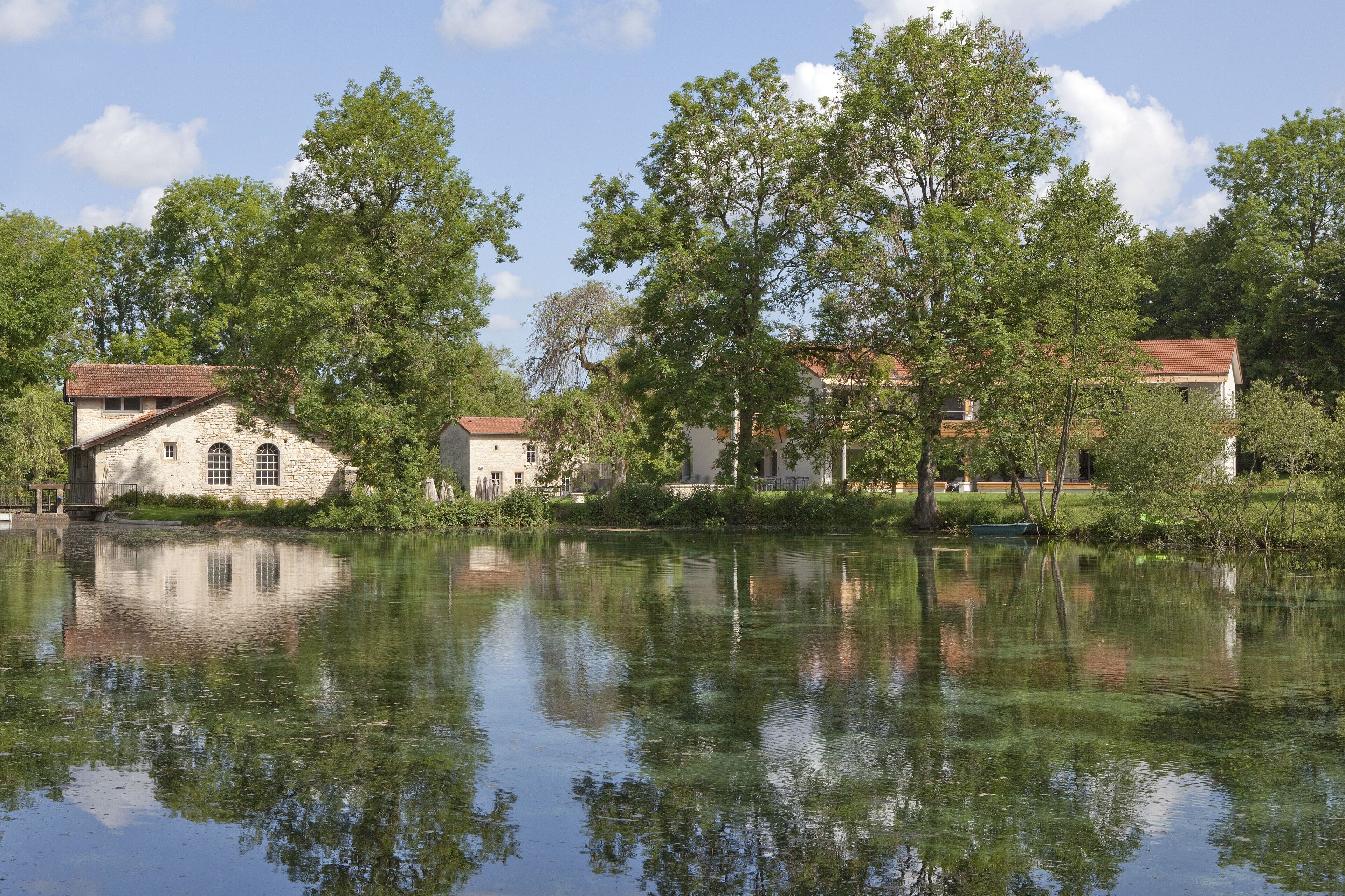 A serene lakeside setting with stone buildings and lush greenery.