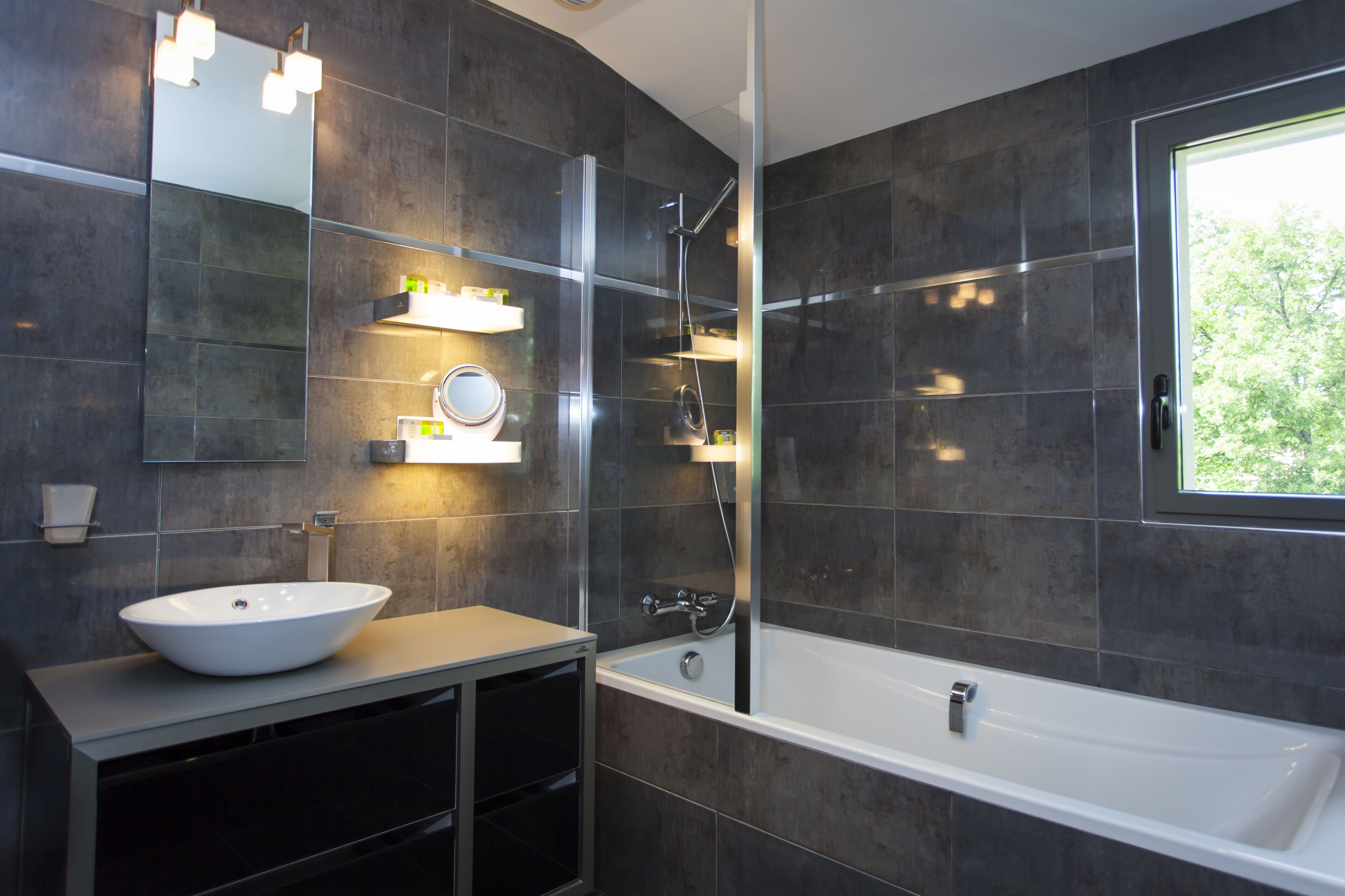 Un baño moderno con una bañera grande, un lavamanos sobre encimera y una ducha con mampara de vidrio.