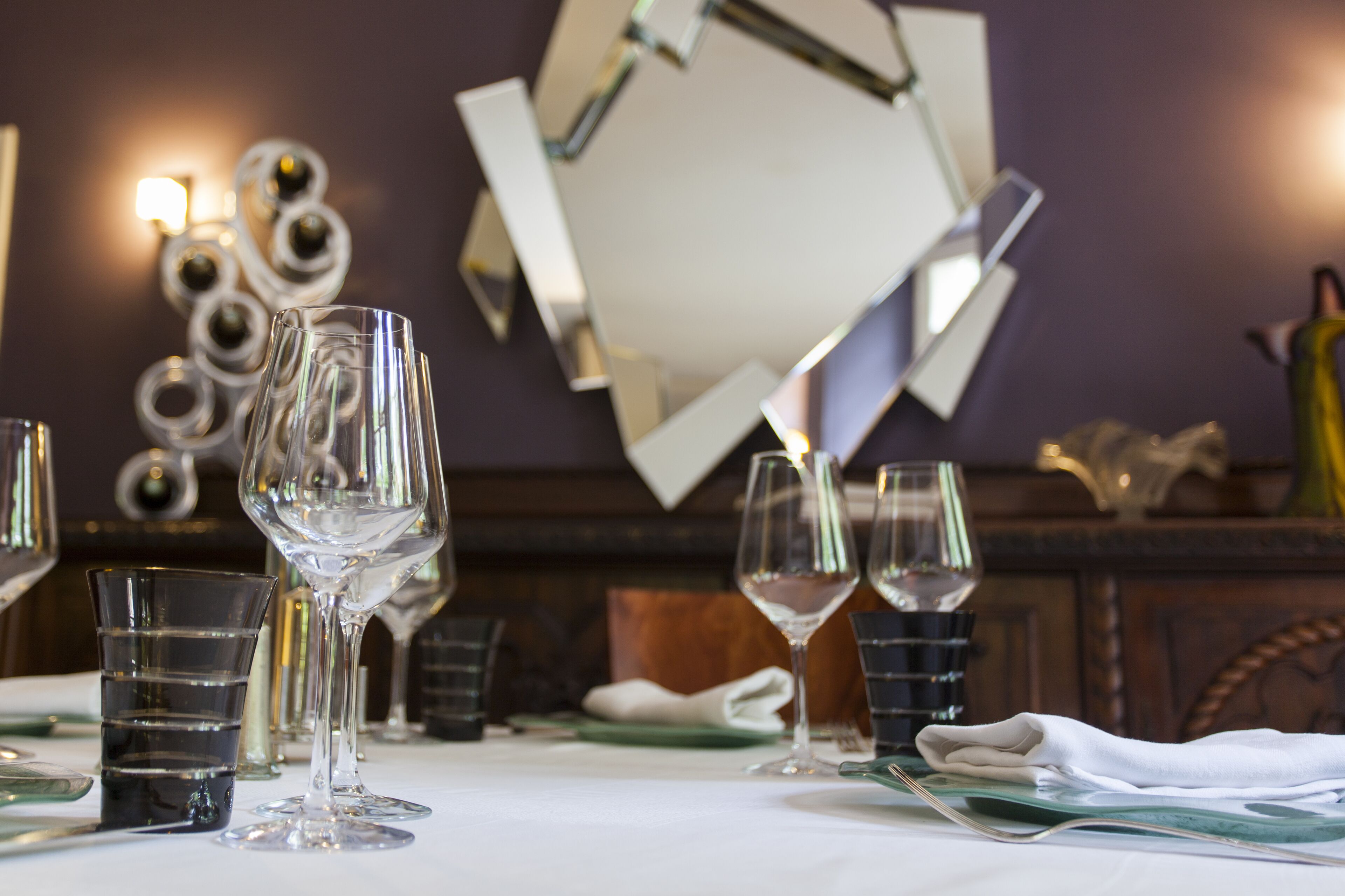 Une table à manger avec plusieurs verres à vin et un miroir qui reflète la pièce.