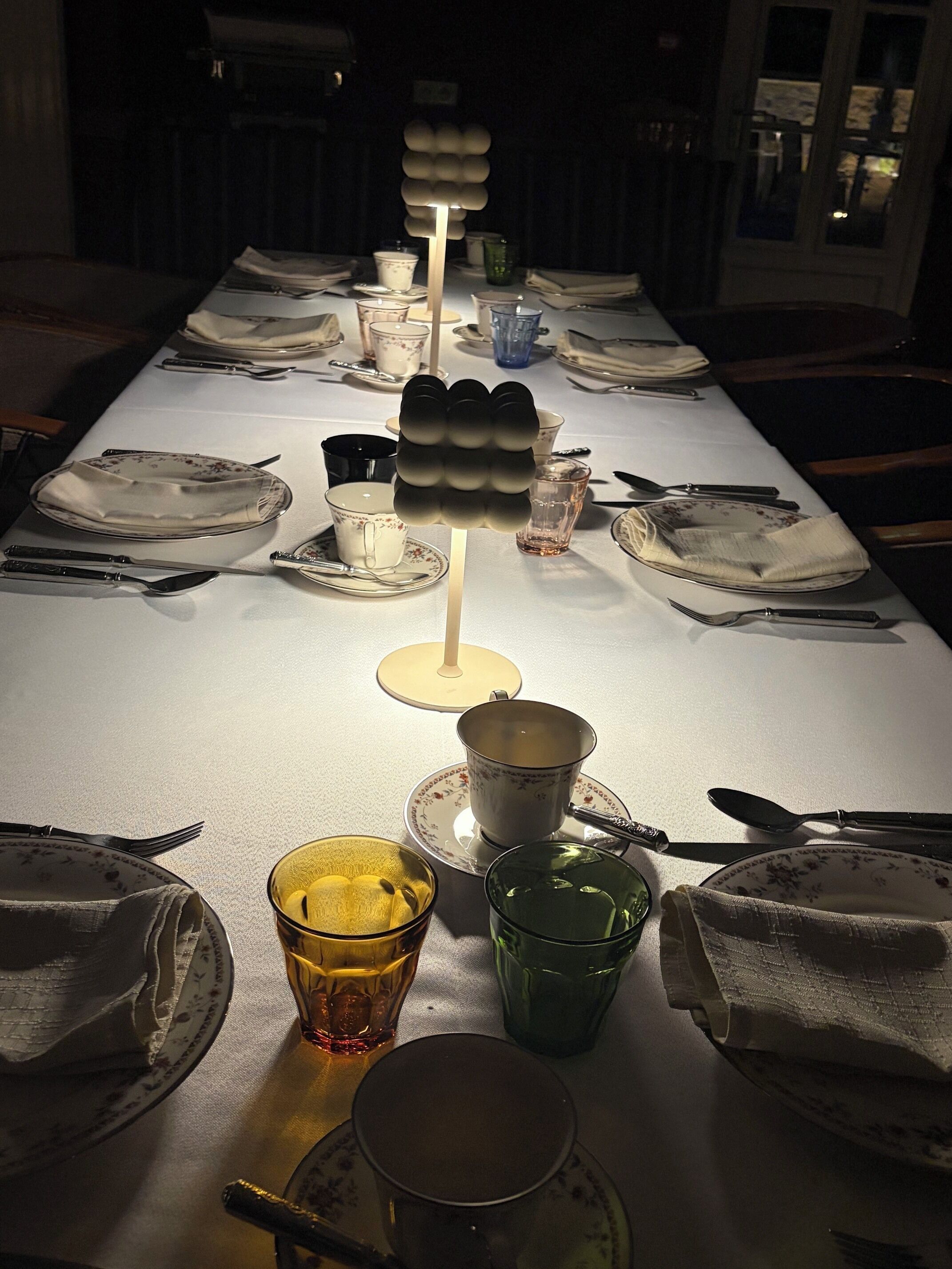 A dining table set with plates, cutlery, and glasses, with a central decorative item.