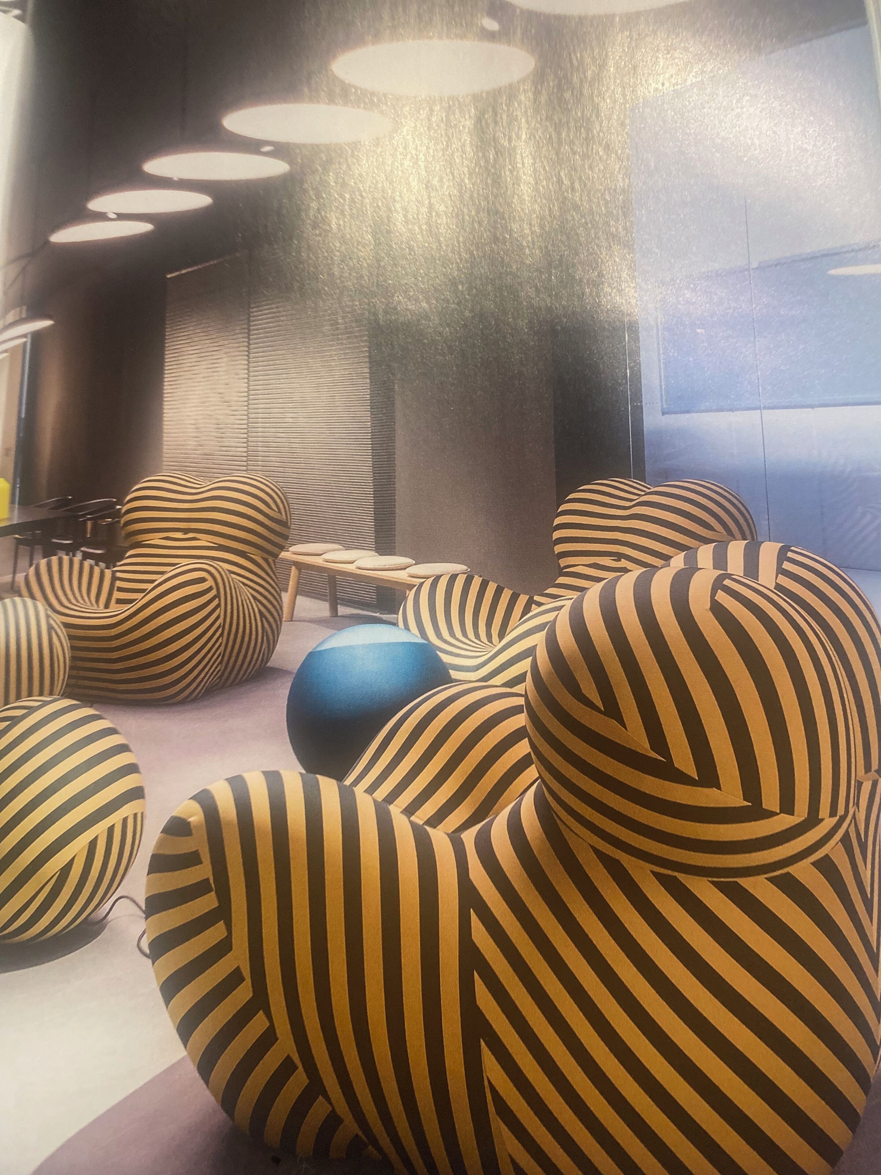 Un interior moderno con sillones orejeros a rayas y una pelota de ejercicio azul.