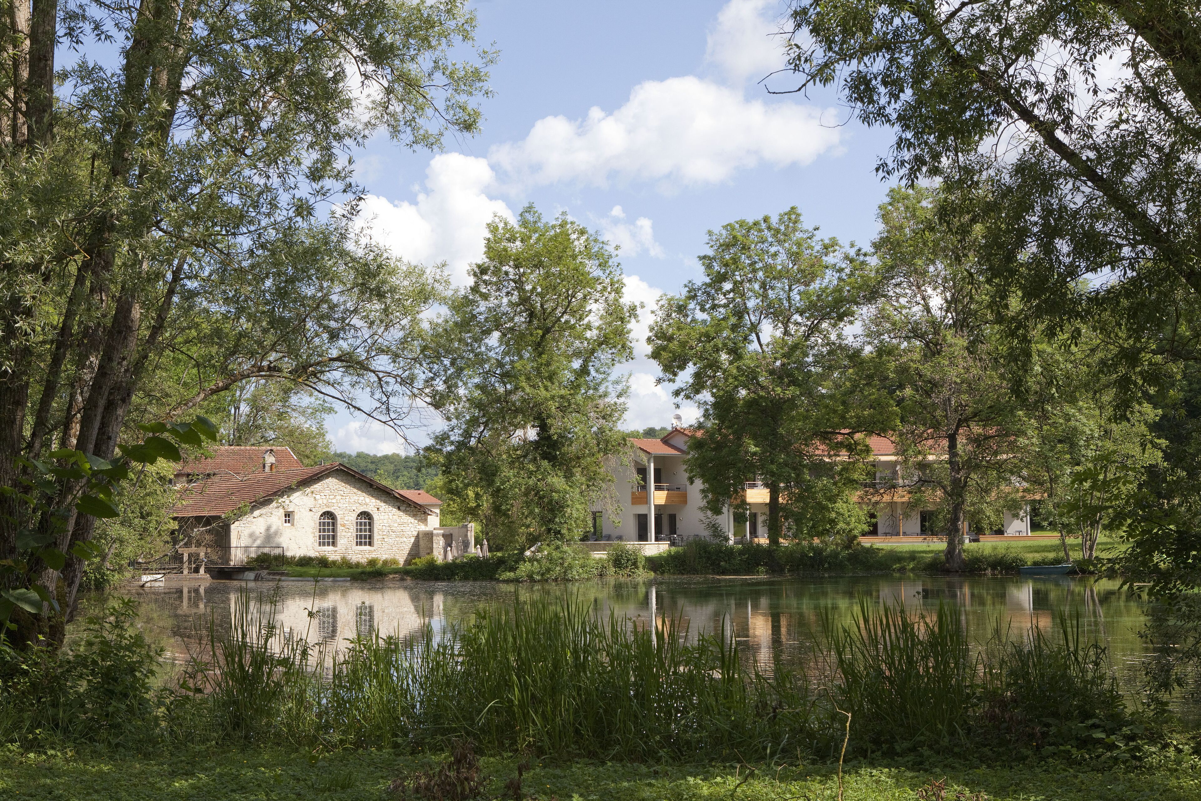 Una propietat a la vora d'un llac amb edificis de pedra, un moll i vegetació exuberanta.