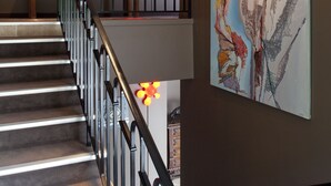 A staircase with a metal railing, a red decorative light fixture, and a large abstract painting on the wall. - Hôtel la Source Bleue (Gudmont)