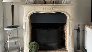 Une cheminée ornée d’une sculpture équestre, un miroir au-dessus et une petite plante en pot placée à côté de la cheminée.