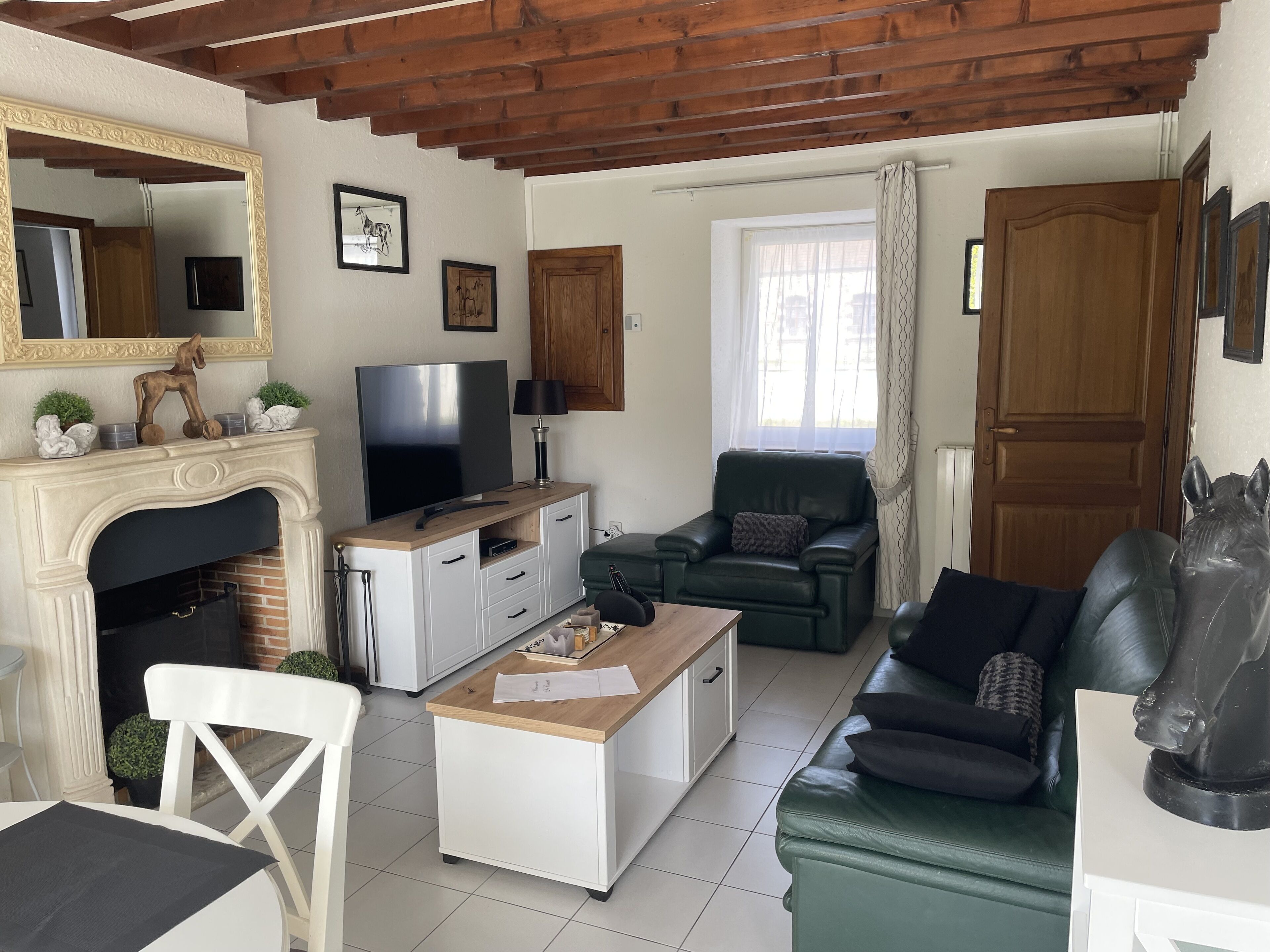 Sala de estar com lareira, televisão, sofá verde, mesa de centro e teto de madeira.