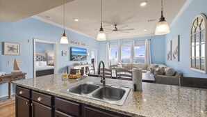 Una cocina moderna con encimeras de granito, doble pileta y luces colgantes.