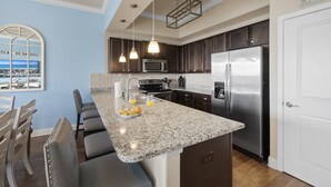 Una cocina moderna con encimeras de granito, electrodomésticos de acero inoxidable y una barra de desayuno.