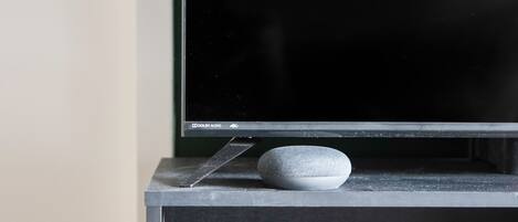A flat-screen TV on a stand with a small, textured object on the stand.
