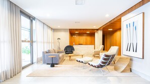 A modern living room with a sofa, armchairs, a coffee table, and a fireplace. - Charlie Edição Jardim Paulista (São Paulo)