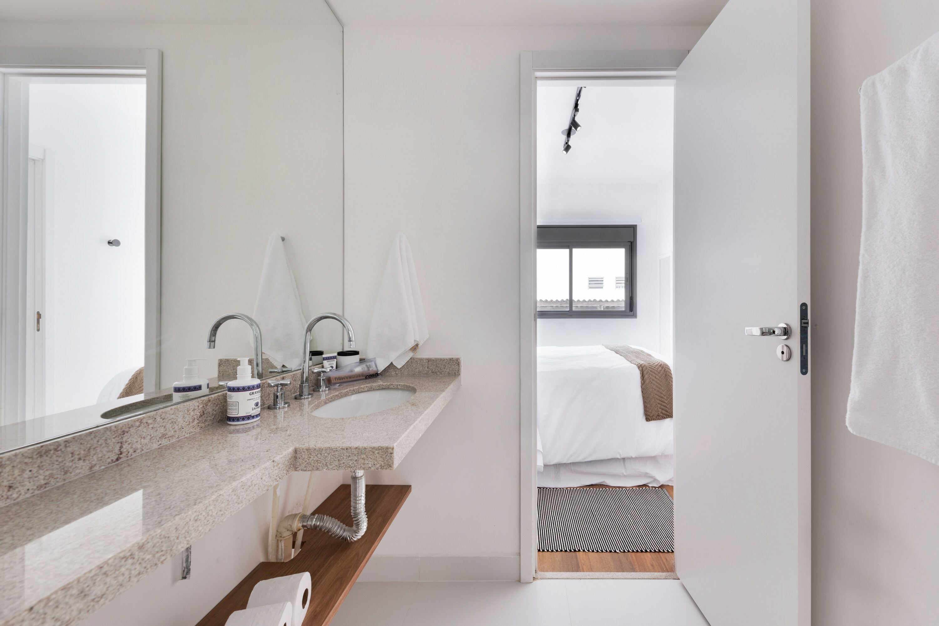 A modern bathroom with two sinks, a large mirror, and a towel rack.