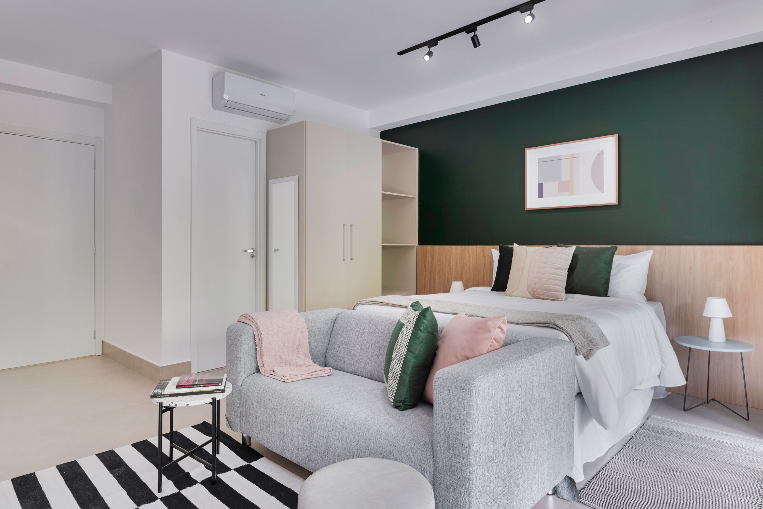 Une chambre à coucher moderne avec un lit, un canapé, une petite table et une table d’appoint.