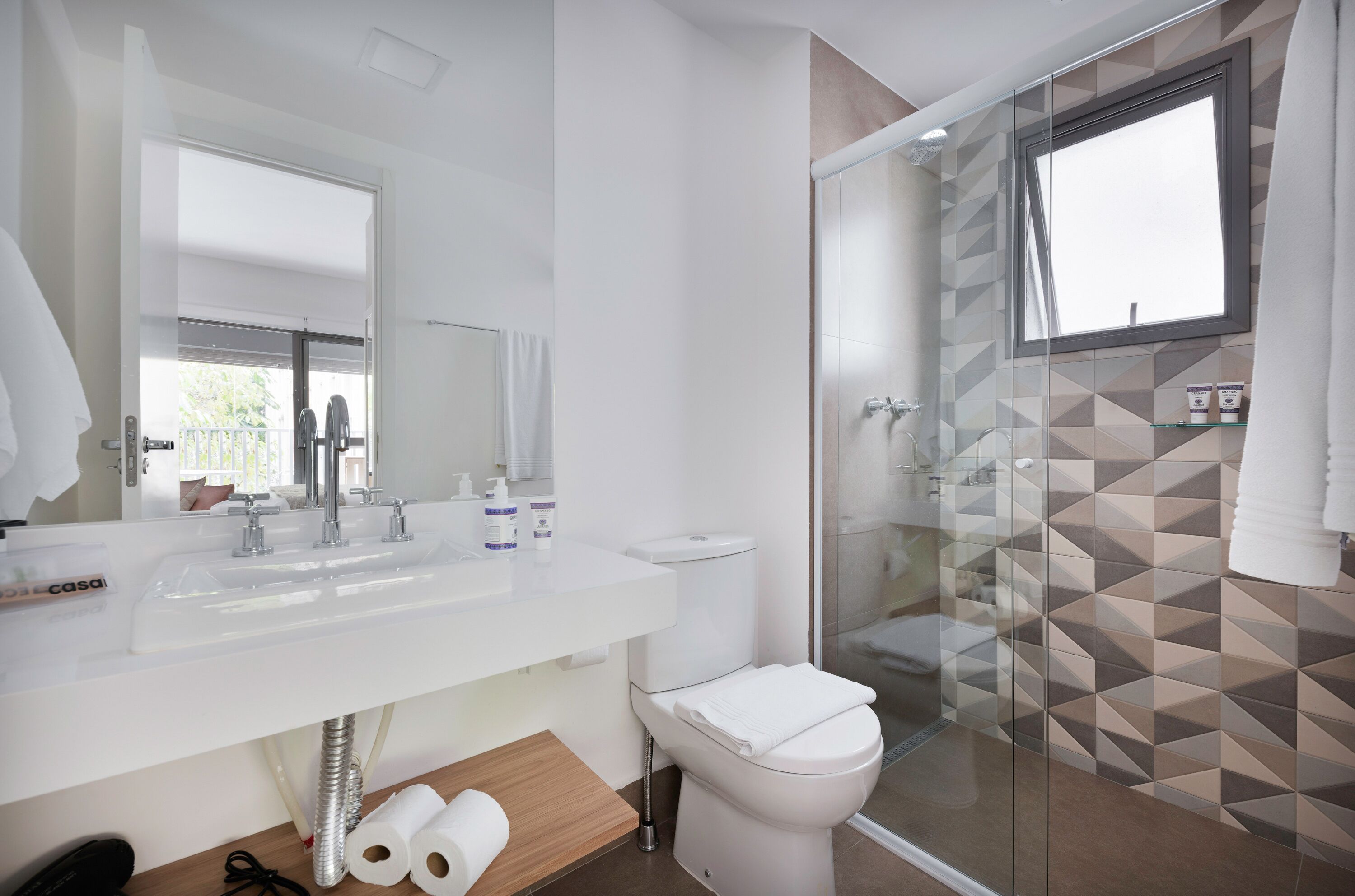 A modern bathroom with a white sink, a toilet, and a glass-enclosed shower.
